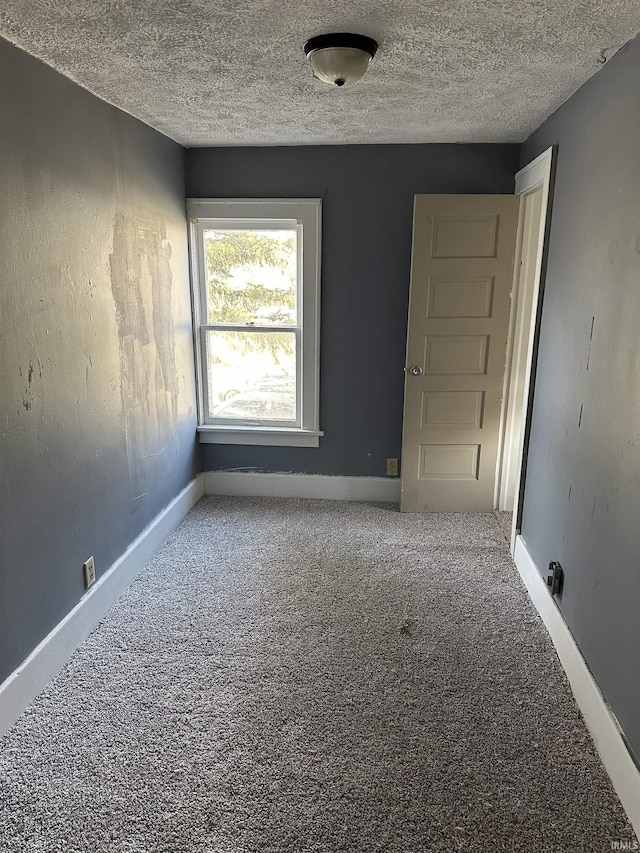 carpeted empty room featuring a textured ceiling