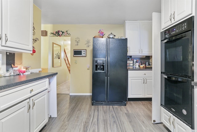 kitchen with black appliances, light hardwood / wood-style floors, and white cabinetry