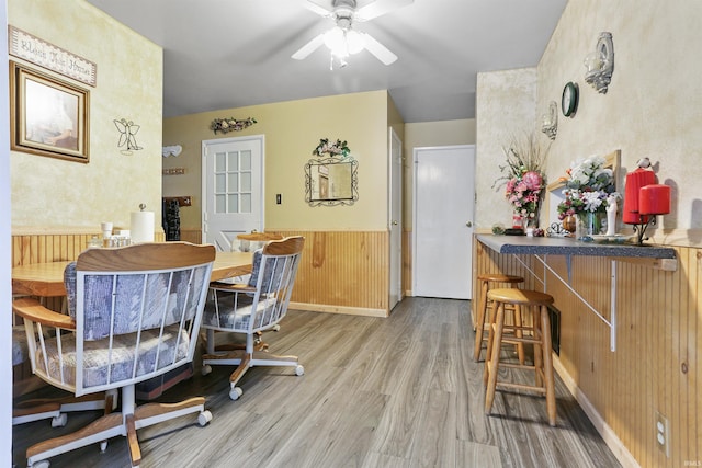 dining room featuring ceiling fan, hardwood / wood-style floors, and wood walls