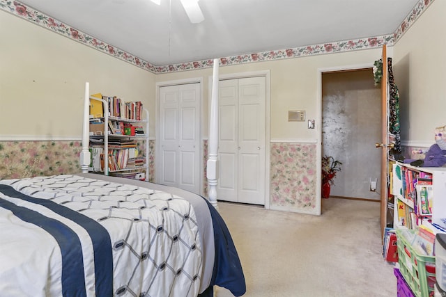 bedroom featuring ceiling fan, light carpet, and multiple closets