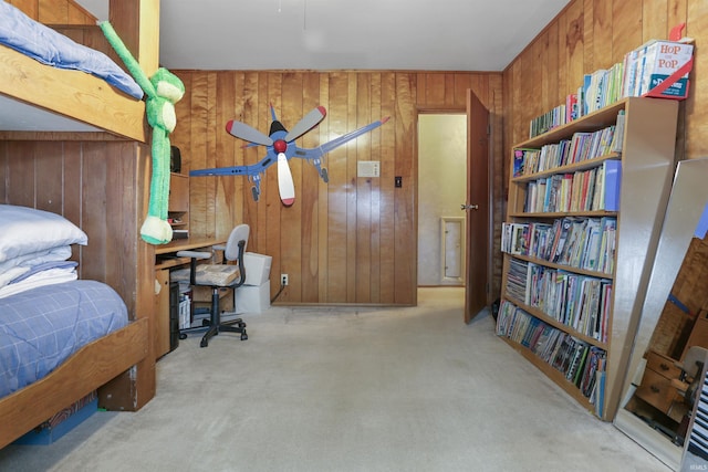 bedroom with ceiling fan, wood walls, and light carpet