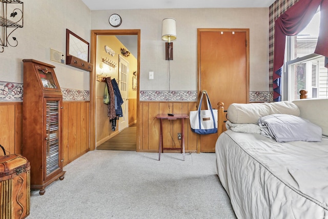 bedroom with light colored carpet and wooden walls