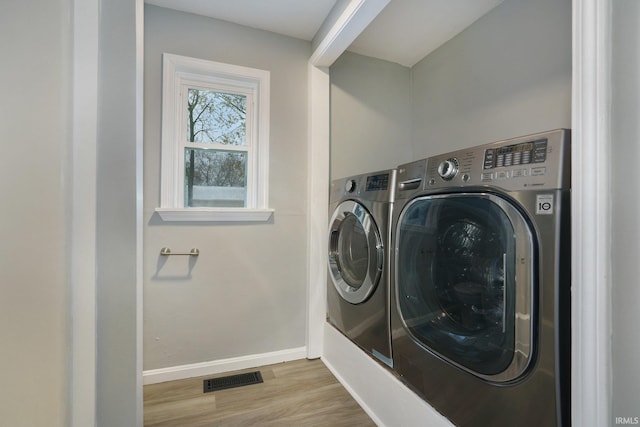 washroom featuring washing machine and dryer and light hardwood / wood-style flooring