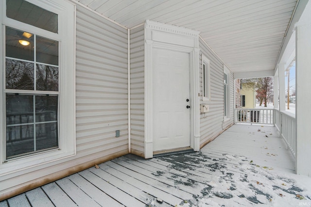 snow covered deck featuring covered porch