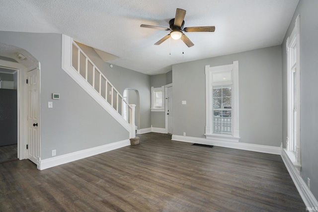 unfurnished living room featuring a wealth of natural light, dark wood-type flooring, and a textured ceiling