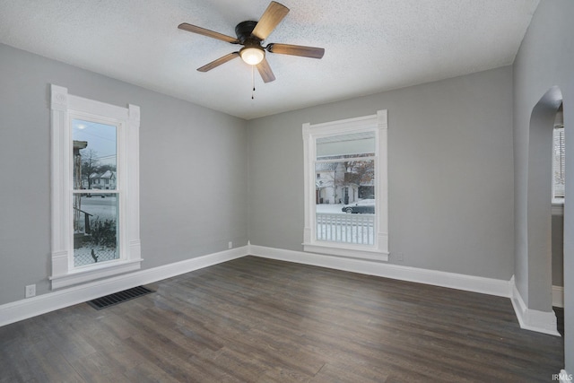 empty room with ceiling fan, dark wood-type flooring, and a textured ceiling