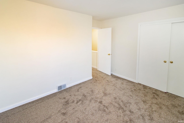 unfurnished bedroom with light colored carpet and a closet