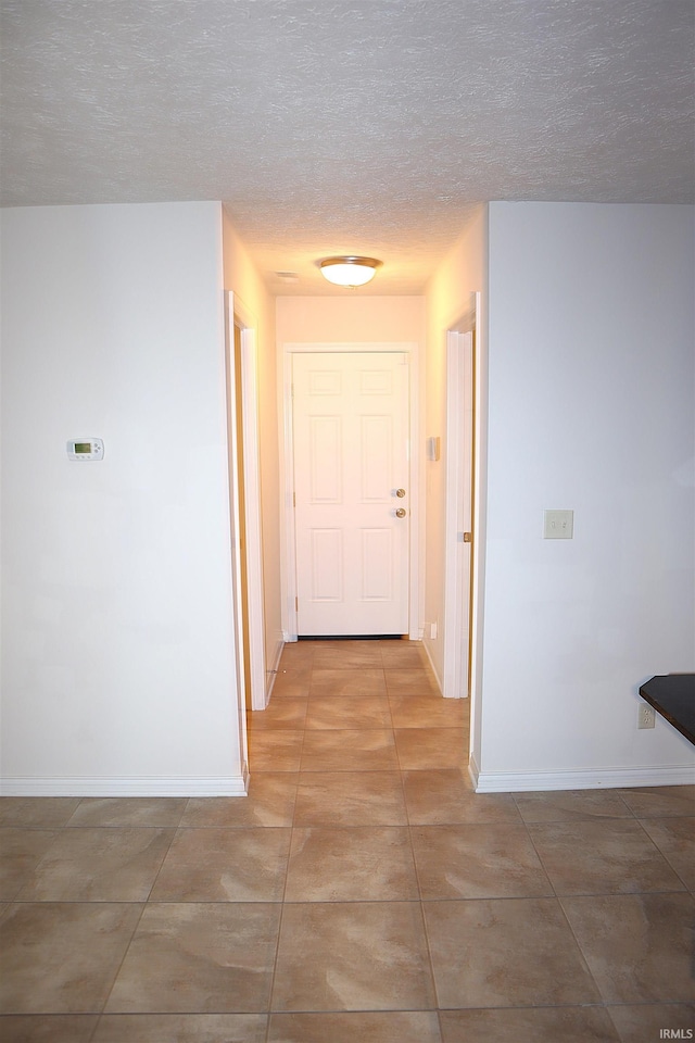 corridor featuring tile patterned floors and a textured ceiling