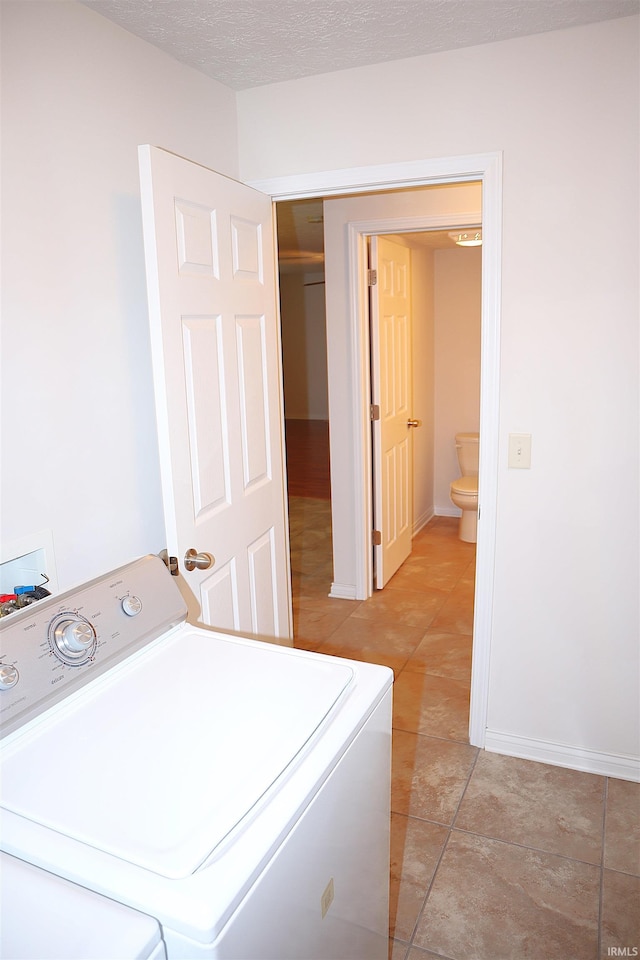 clothes washing area featuring light tile patterned floors, a textured ceiling, and washer / clothes dryer