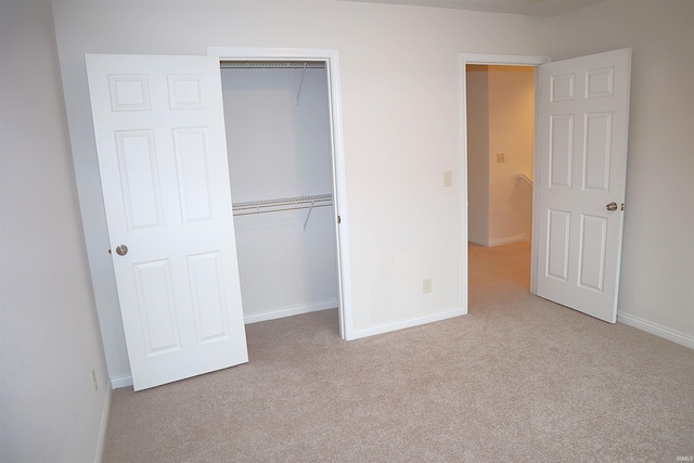 unfurnished bedroom with light carpet and a closet