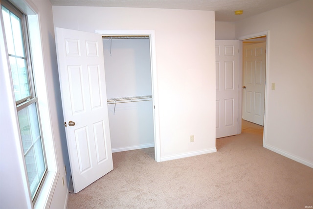 unfurnished bedroom with light carpet and a closet