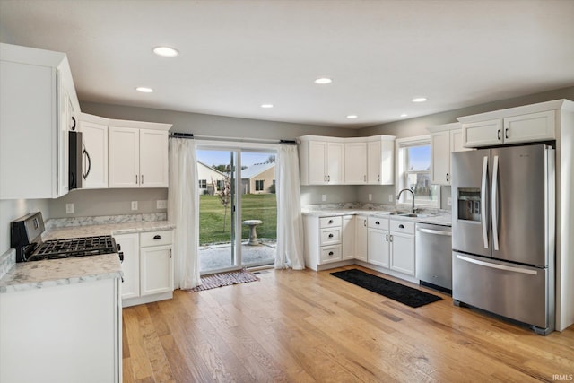 kitchen featuring white cabinets, light wood-type flooring, stainless steel appliances, and sink