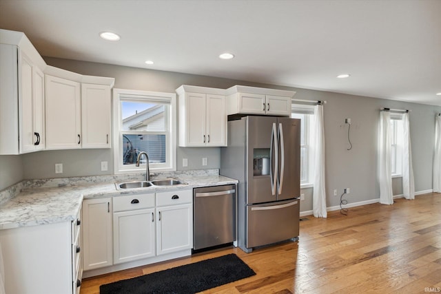 kitchen featuring white cabinets, sink, stainless steel appliances, and light hardwood / wood-style flooring