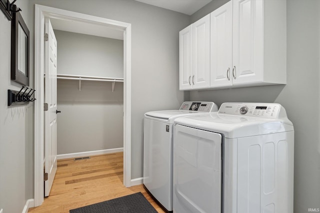 washroom featuring cabinets, light hardwood / wood-style flooring, and washer and dryer