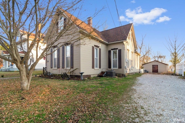 view of front of house with a garage, an outdoor structure, a front yard, and central AC