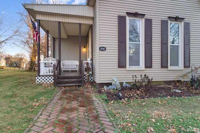 entrance to property featuring a lawn and a porch