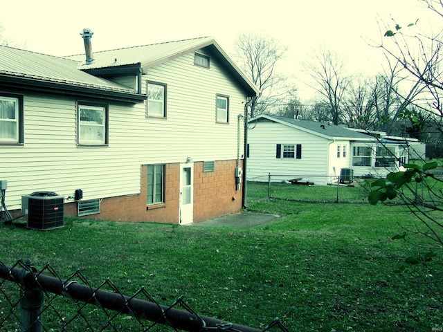 rear view of property featuring a yard and central AC unit