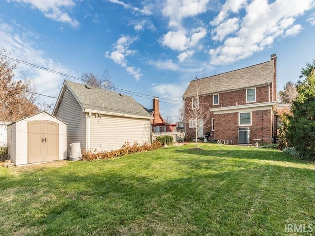 rear view of property with a lawn, a storage unit, and central air condition unit