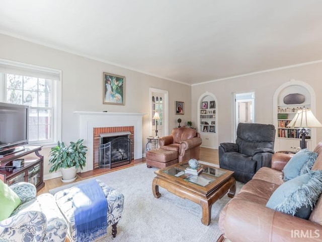 living room featuring wood-type flooring, ornamental molding, and a brick fireplace