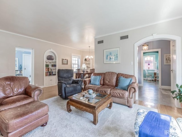 living room with a chandelier, crown molding, and light hardwood / wood-style floors