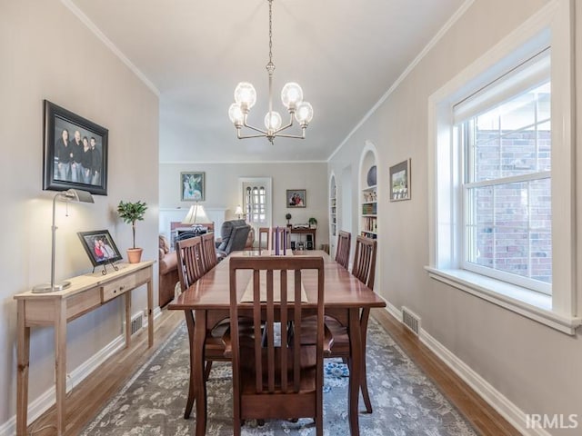 dining space with dark hardwood / wood-style floors, an inviting chandelier, and crown molding