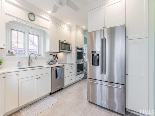 kitchen featuring white cabinets, sink, ceiling fan, appliances with stainless steel finishes, and light hardwood / wood-style floors