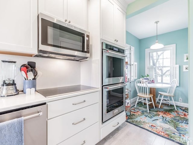 kitchen featuring white cabinets, hanging light fixtures, and appliances with stainless steel finishes