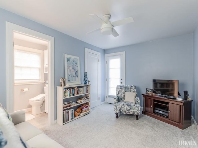 living area featuring light carpet and ceiling fan