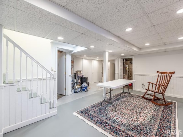 game room featuring concrete flooring, a paneled ceiling, and water heater