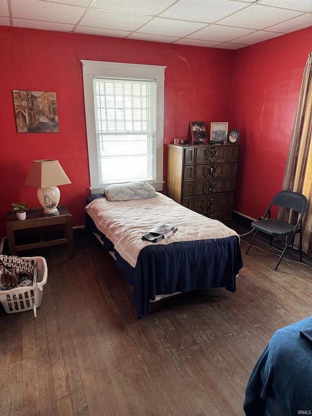 bedroom with a paneled ceiling and wood-type flooring