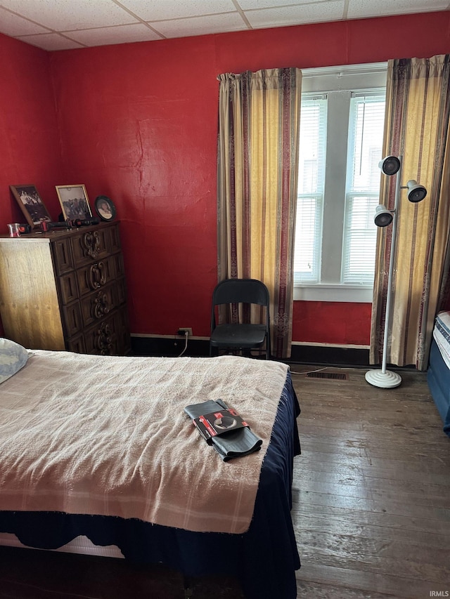 bedroom with a paneled ceiling and dark wood-type flooring