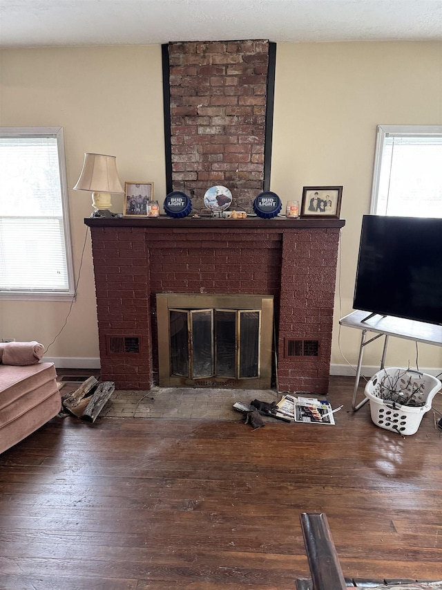 living room with dark hardwood / wood-style floors, a brick fireplace, and a healthy amount of sunlight