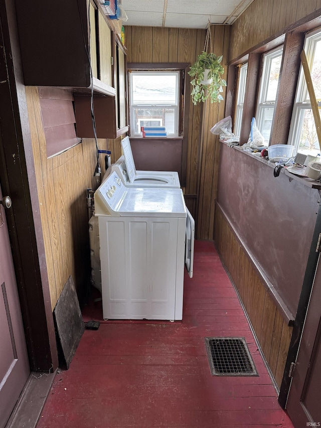 washroom with washing machine and clothes dryer and wooden walls