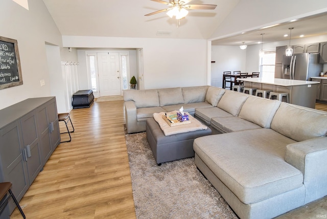 living room with ceiling fan, light wood-type flooring, and lofted ceiling