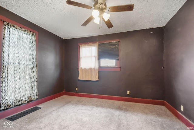 carpeted empty room featuring ceiling fan and a textured ceiling