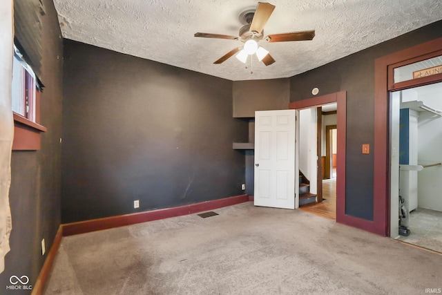 unfurnished bedroom with carpet flooring, ceiling fan, and a textured ceiling