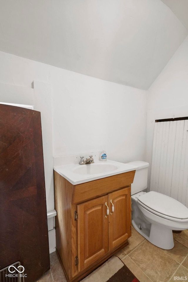 bathroom featuring tile patterned flooring, vanity, lofted ceiling, and toilet