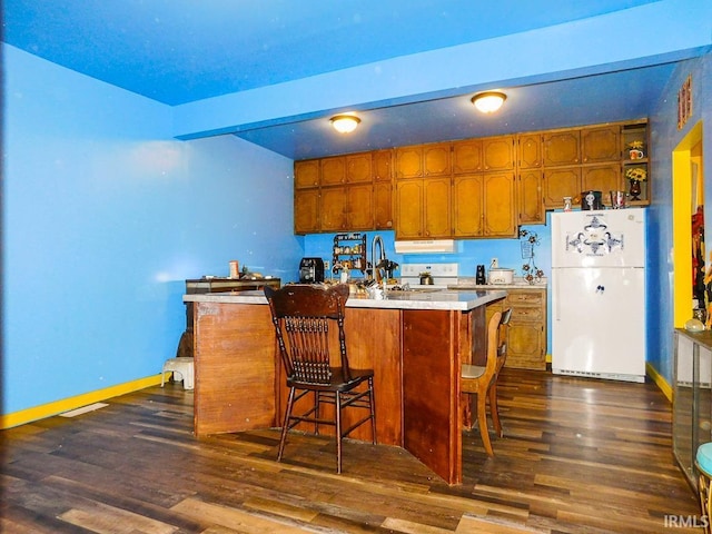 kitchen with a kitchen bar, dark hardwood / wood-style flooring, a center island, and white appliances