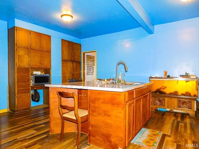 kitchen with a center island, sink, dark hardwood / wood-style flooring, beamed ceiling, and a breakfast bar area