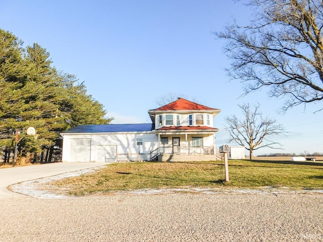 view of front of property featuring a garage, covered porch, and a front yard