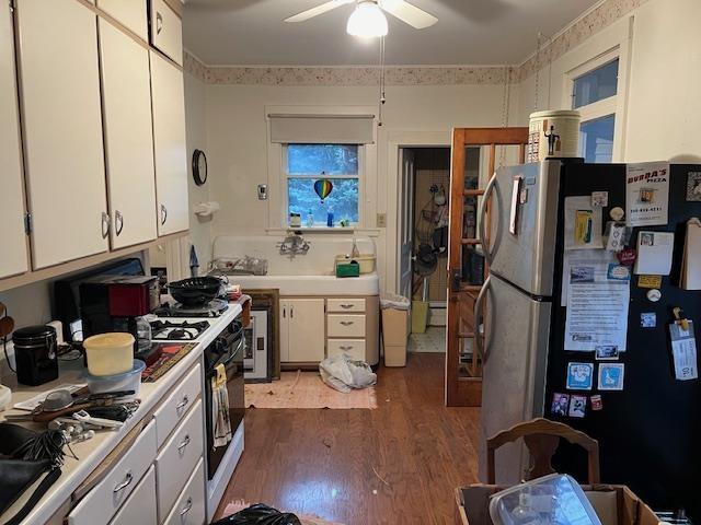 kitchen with stainless steel fridge, ceiling fan, dark wood-type flooring, white range with gas stovetop, and white cabinetry