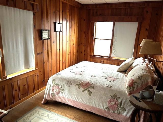 bedroom with hardwood / wood-style floors and wood walls