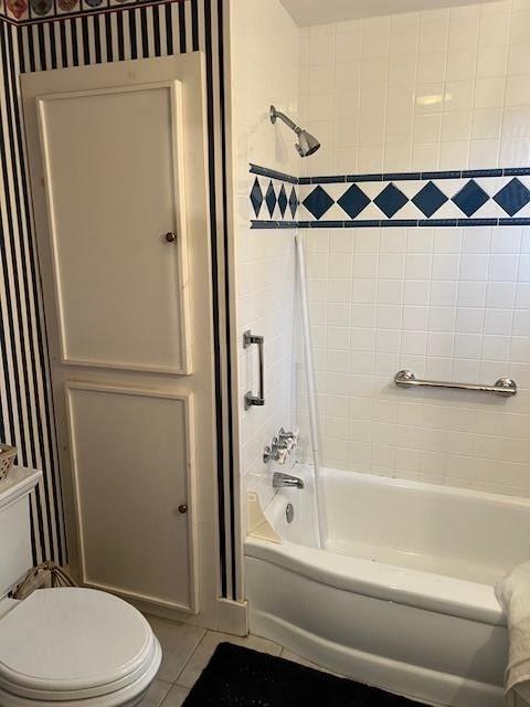 bathroom with tile patterned flooring, tiled shower / bath combo, and toilet