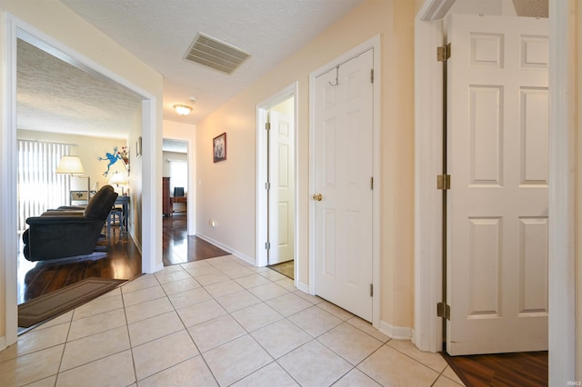 hall featuring light tile patterned floors and a textured ceiling