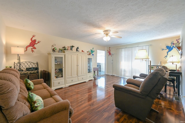 living room with a textured ceiling, ceiling fan, and dark wood-type flooring