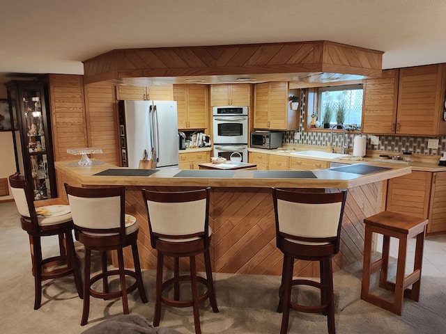 kitchen featuring wood walls, sink, tasteful backsplash, light colored carpet, and stainless steel appliances