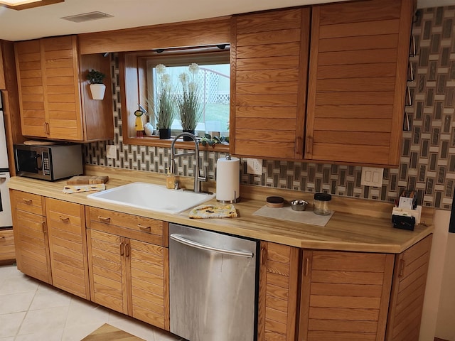 kitchen featuring decorative backsplash, sink, light tile patterned floors, and stainless steel appliances