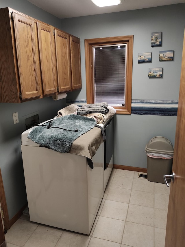 clothes washing area featuring cabinets, light tile patterned floors, and separate washer and dryer