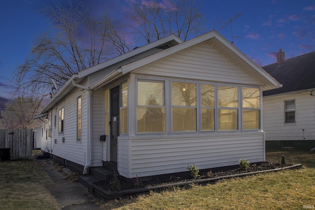 property exterior at dusk featuring a sunroom