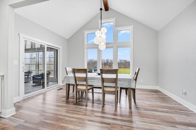 dining room featuring beam ceiling, high vaulted ceiling, and light hardwood / wood-style floors